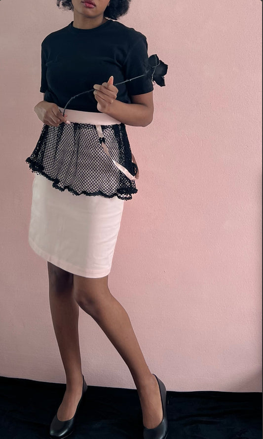 A model wearing KimYoung's knee-length pencil skirt with a black fishnet peplum and KimYoung's signature black ribbon chain with a black bow with pearl on it, paired with a black top and black heels. The model is also holding a black rose.